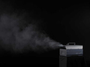 Fog machine emitting mist in a dark setting.
