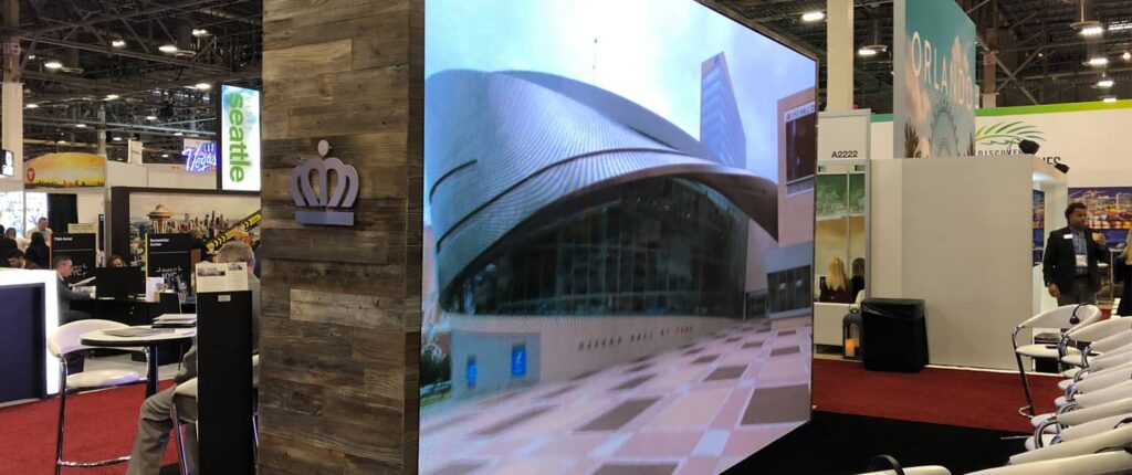 Trade show booth showcasing various city displays and attendees.
