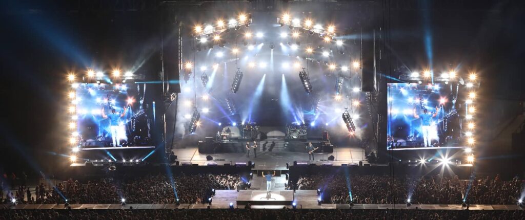 Concert stage with bright lights and large audience.