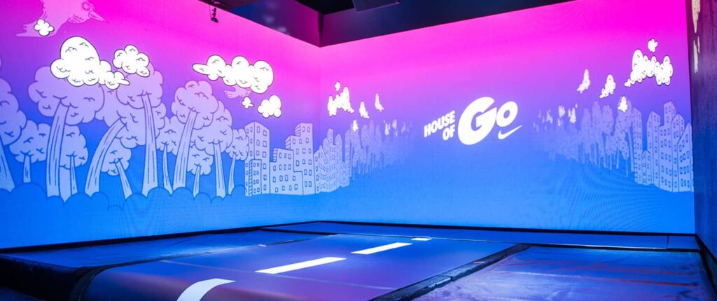 Indoor trampoline area with vibrant sky and cityscape mural.