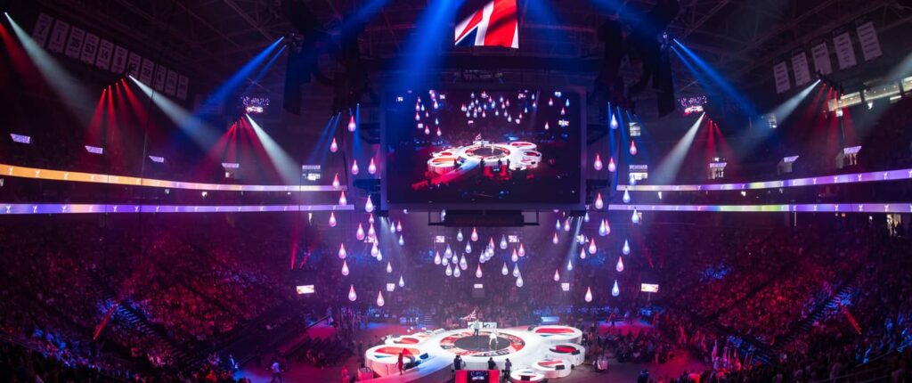 An arena event with a colorful light show and large audience.