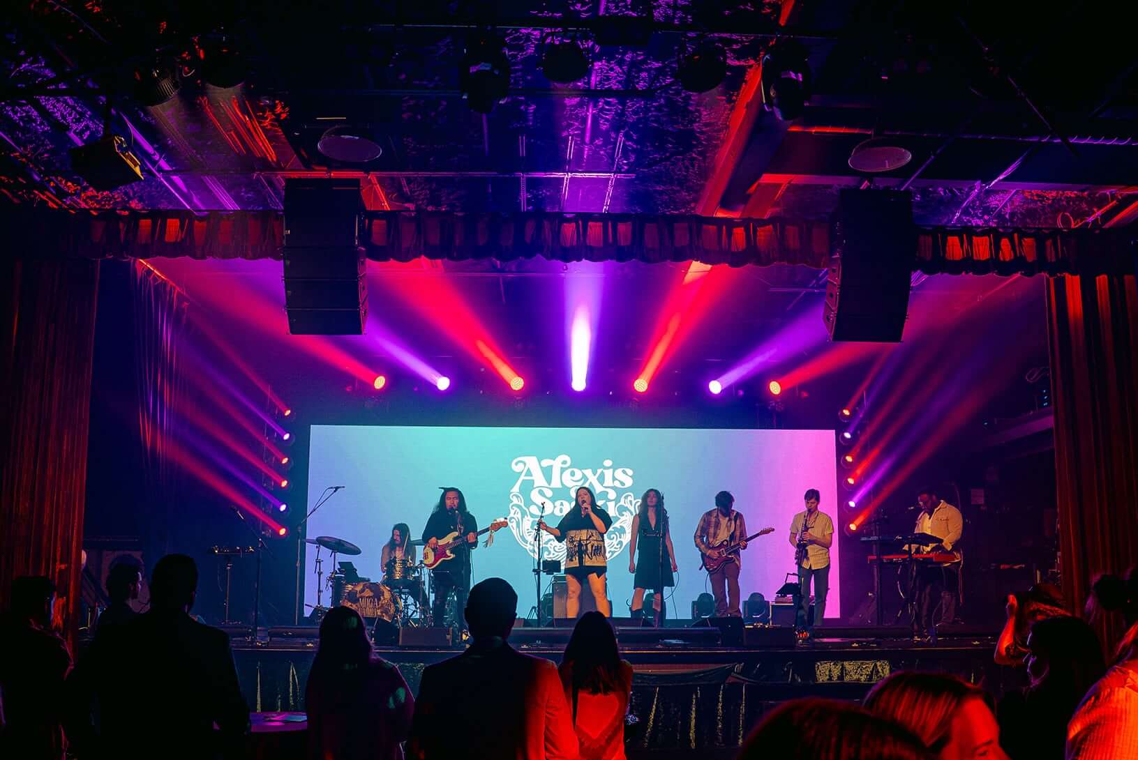 Live band performing on illuminated stage with LED backdrop at corporate event venue