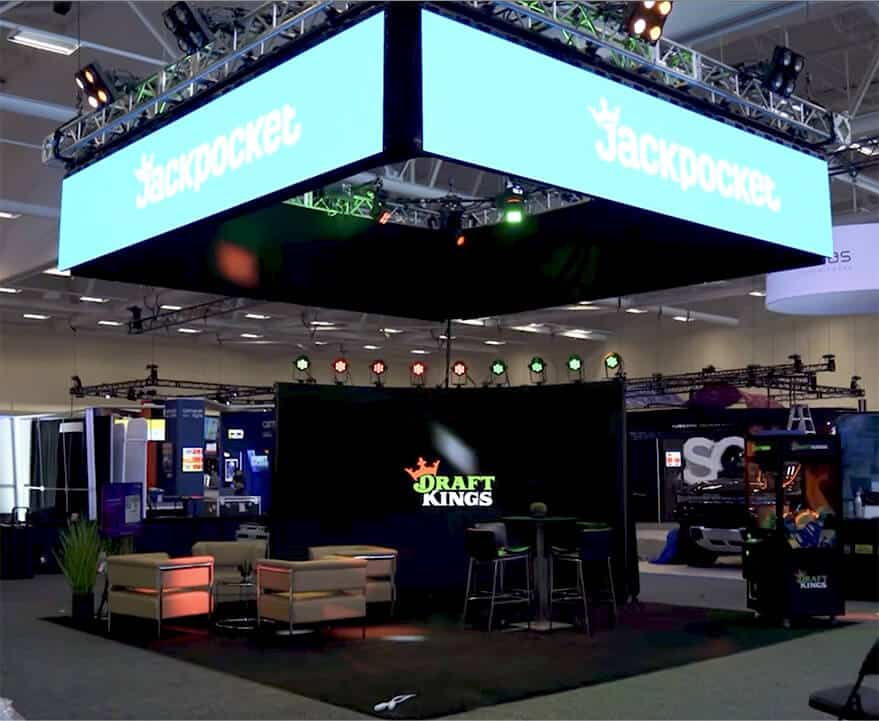DraftKings trade show booth with suspended LED displays and corporate branding at convention