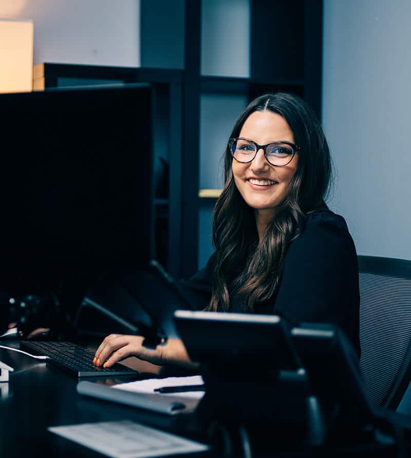 Smiling event producer at workstation managing corporate event production workflow